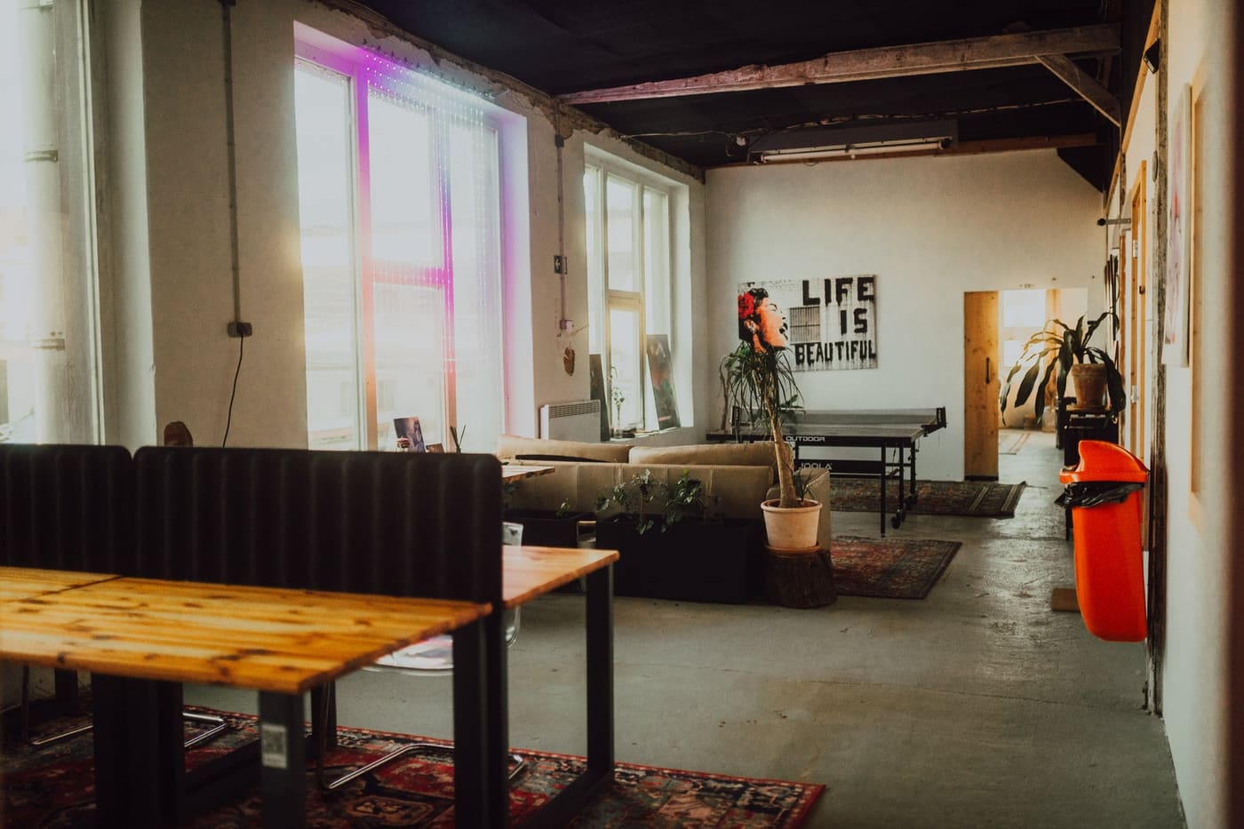 Coworking Area mit Tischen, Pflanzen und Tischtennisplatte
